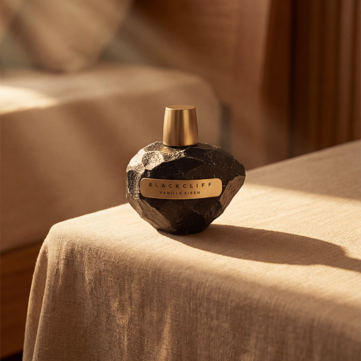 Blackcliff vanilla-silver perfume bottle on a beige surface with a blurred background